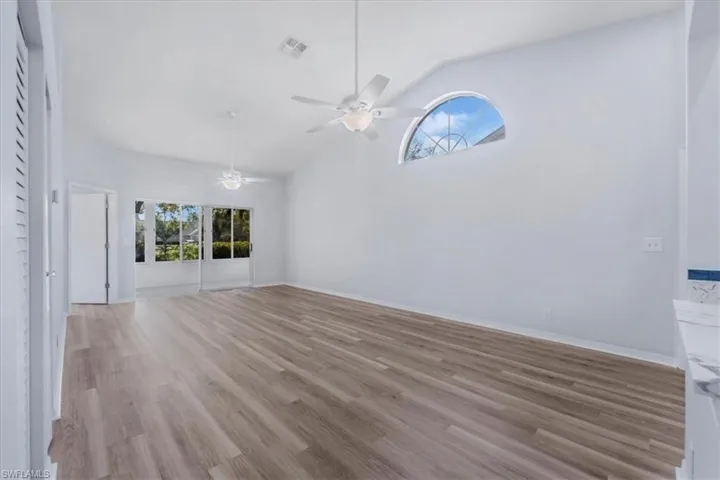 Empty room with healthy amount of natural light, light wood-style floors, high vaulted ceiling, and a ceiling fan