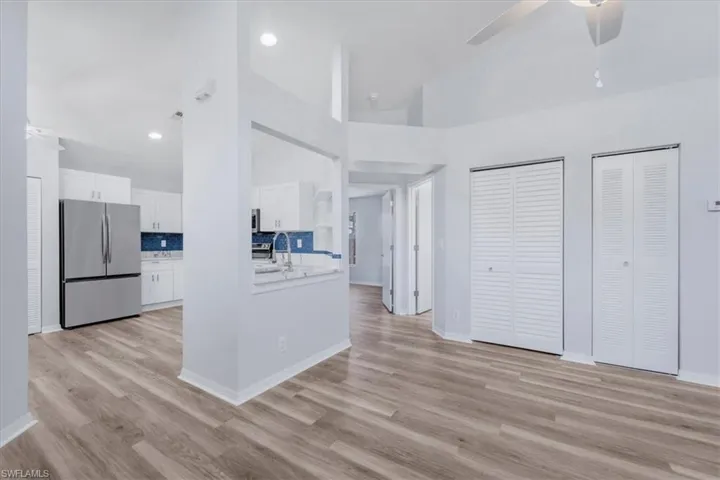 Kitchen with white cabinets, freestanding refrigerator, tasteful backsplash, light countertops, and light wood finished floors