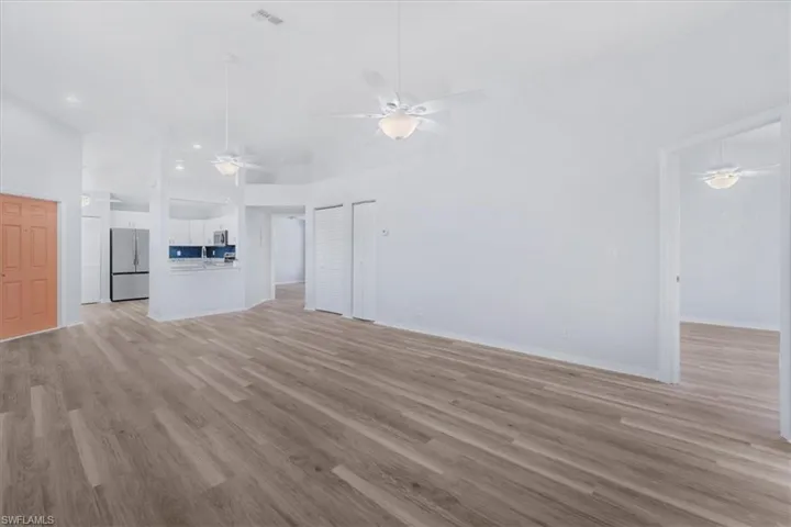 Unfurnished living room featuring light wood-style floors, ceiling fan, and a towering ceiling