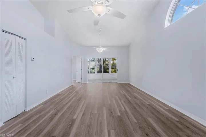 Unfurnished living room featuring a towering ceiling, wood finished floors, and french doors