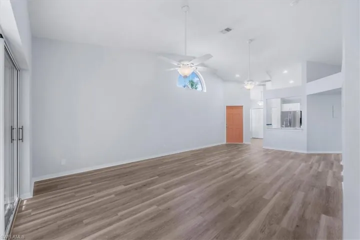 Unfurnished living room featuring light wood finished floors, high vaulted ceiling, and ceiling fan