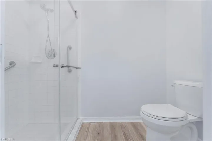Bathroom with a shower stall and wood finished floors