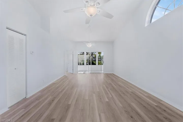 Unfurnished living room featuring a towering ceiling, light wood finished floors, french doors, and ceiling fan