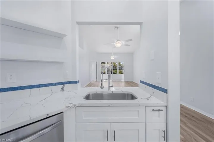 Kitchen with light stone counters, wood finished floors, dishwasher, and open shelves