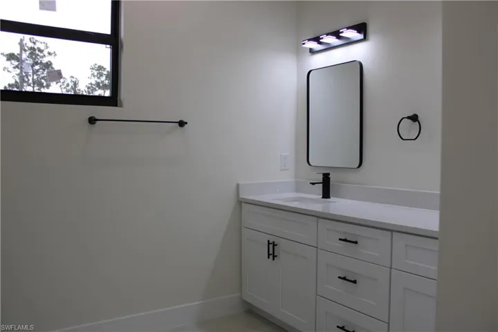 Bathroom featuring a white vanity with shaker-style cabinetry, matte black hardware, and a light-colored speckled countertop