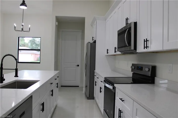 Modern kitchen featuring white shaker cabinetry, stainless steel appliances, and light-toned countertops