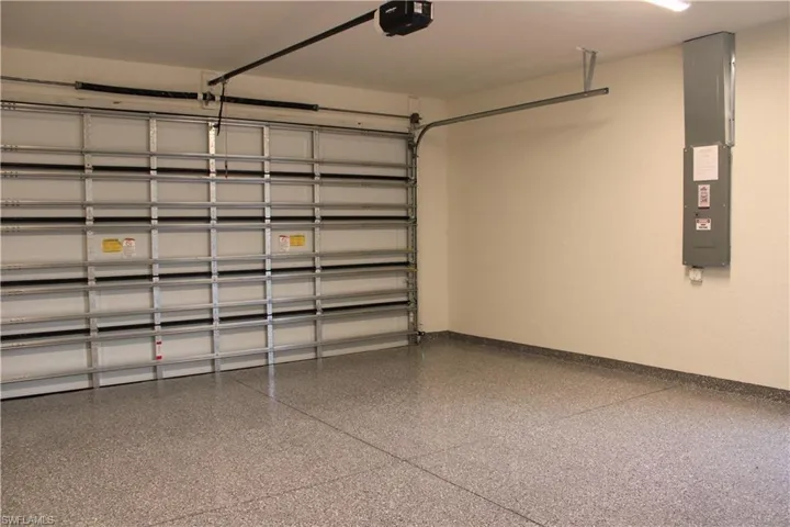 Spacious garage featuring a durable epoxy-coated concrete floor, white interior walls, and a sectional overhead garage door