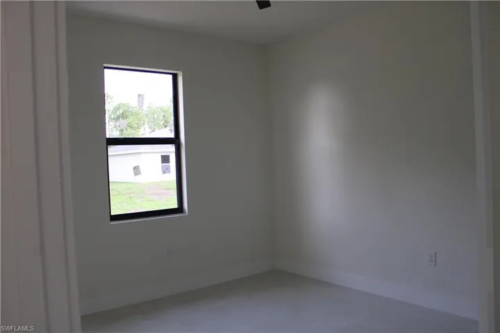 Neutral-toned room featuring a single window with black framing, light-colored walls, and tile flooring