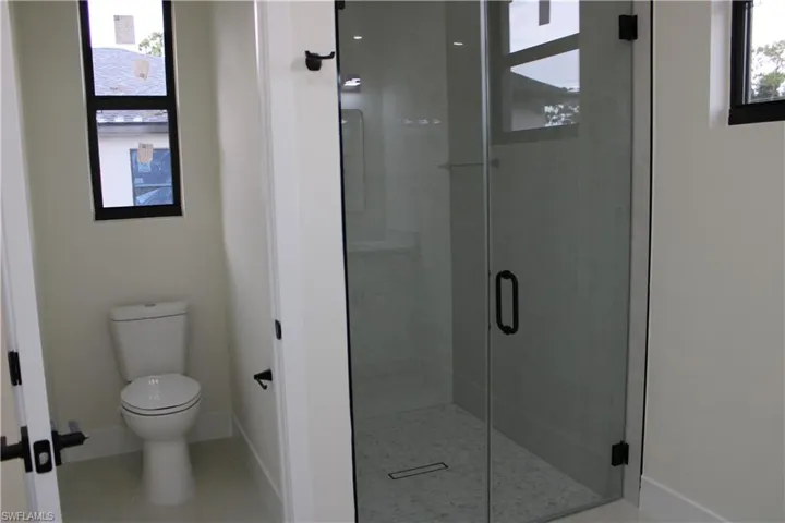 Contemporary bathroom featuring a frameless glass shower enclosure, a linear drain, and white hexagonal tile flooring within the shower