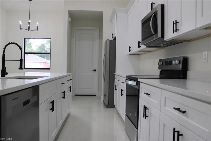 Modern kitchen featuring white cabinetry, light-colored countertops, and stainless steel appliances