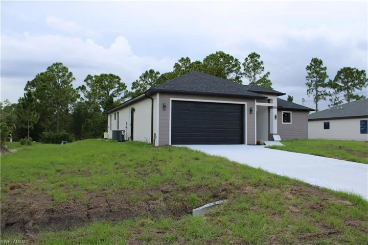 Contemporary single-story residence featuring a two-car garage with a dark panel door, a concrete driveway, and an exterior finished with stucco and siding