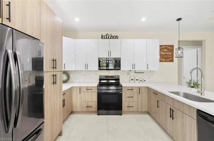 Modern kitchen featuring two-tone cabinetry with light wood-finish lower cabinets and glossy white upper cabinets