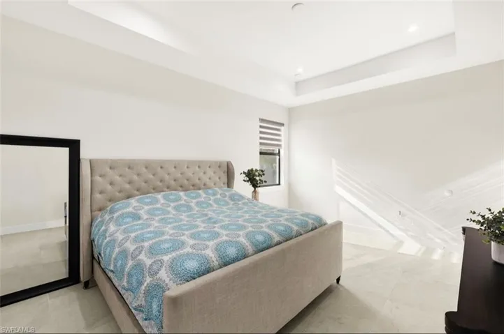Spacious room featuring a tray ceiling, recessed lighting, and large format tile flooring