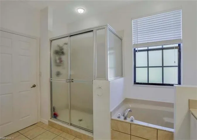 Full bathroom featuring a shower stall, light tile patterned flooring, a garden tub, and vanity