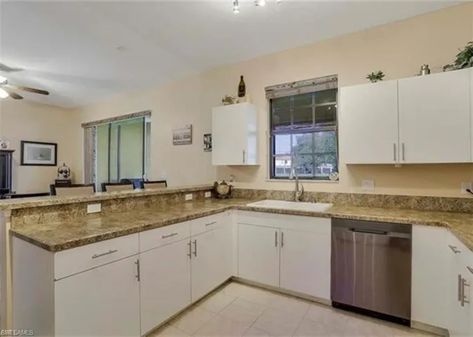 Kitchen featuring white cabinetry, stainless steel dishwasher, and a peninsula