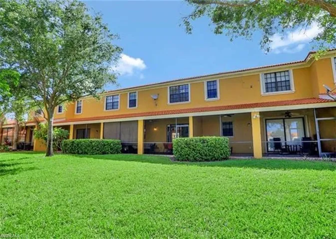 Rear view of property with a lawn, stucco siding, and a sunroom