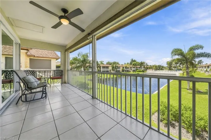 Screened balcony with a ceiling fan, sliding glass doors, tile flooring, and a water feature beyond