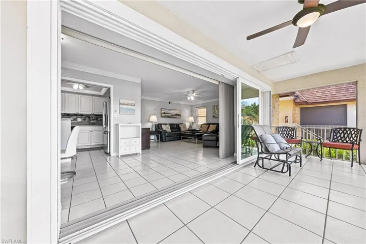 Expansive sliding glass doors open to a tiled outdoor living space with a ceiling fan