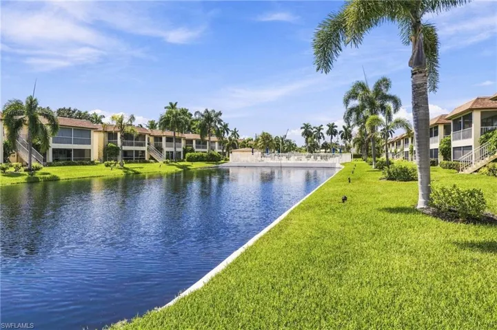 Waterfront property featuring extensive landscaping, mature palm trees, and multiple buildings with screened balconies