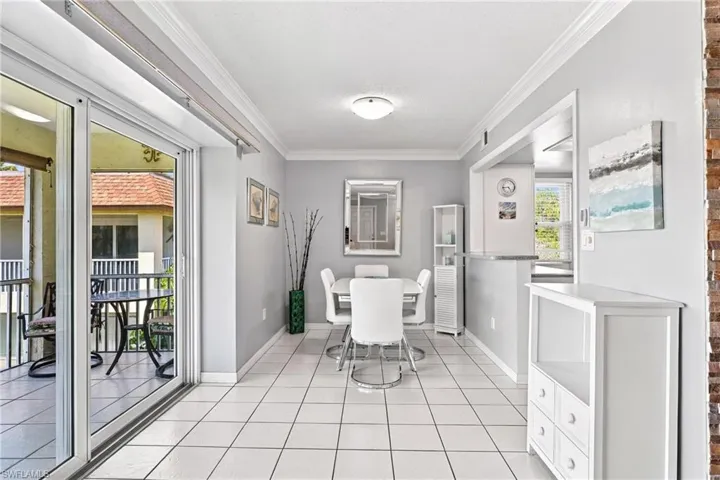 Sliding glass doors, tile flooring, crown molding, a built-in breakfast bar, and an exterior balcony