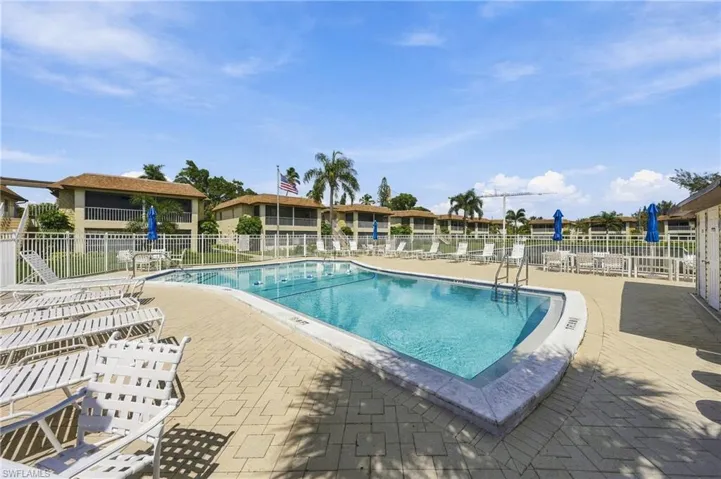 Fenced outdoor pool with an integrated ladder, surrounded by a paver deck