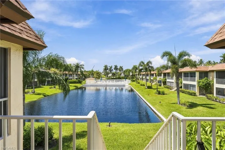 Expansive water feature with lush green landscaping, framed by mature palm trees and residential structures