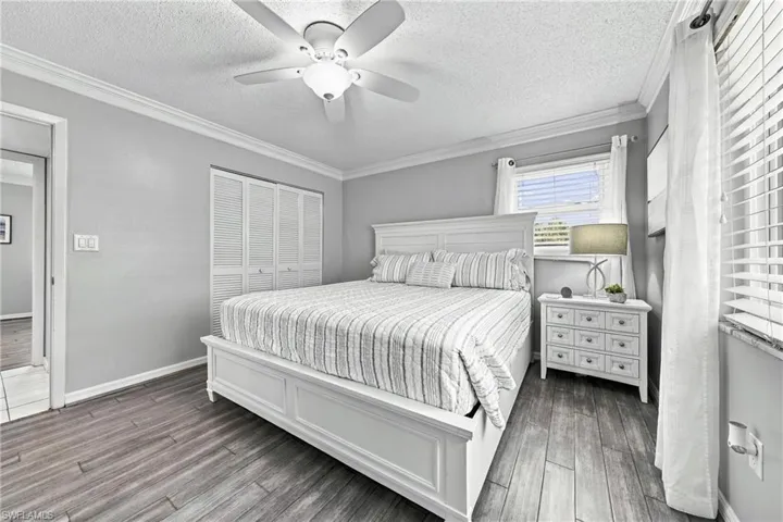 Wood-finish flooring throughout, louvered bi-fold closet doors, ceiling fan with integrated lighting, and crown molding