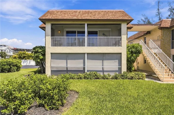 Two-story stucco exterior with a screened upper balcony, lower level screened enclosure, and a brown shingle roof