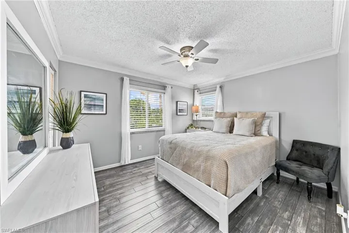 Wood-finish flooring with a ceiling fan light fixture and crown molding