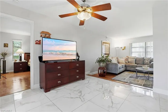 Living room with ceiling fan and light marble finish floors