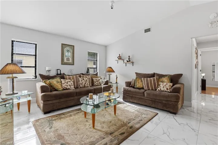 Living room featuring lofted ceiling and light marble finish floors
