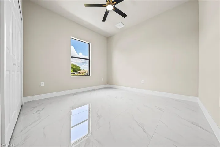 Unfurnished bedroom with light marble finish flooring and ceiling fan