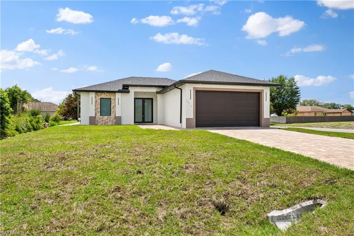 Prairie-style home with driveway, stucco siding, and an attached garage