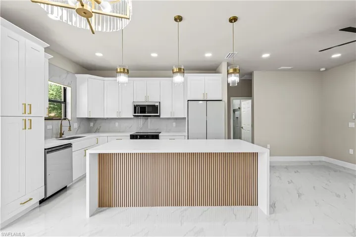 Kitchen featuring a center island, stainless steel appliances, tasteful backsplash, white cabinets, and light stone countertops