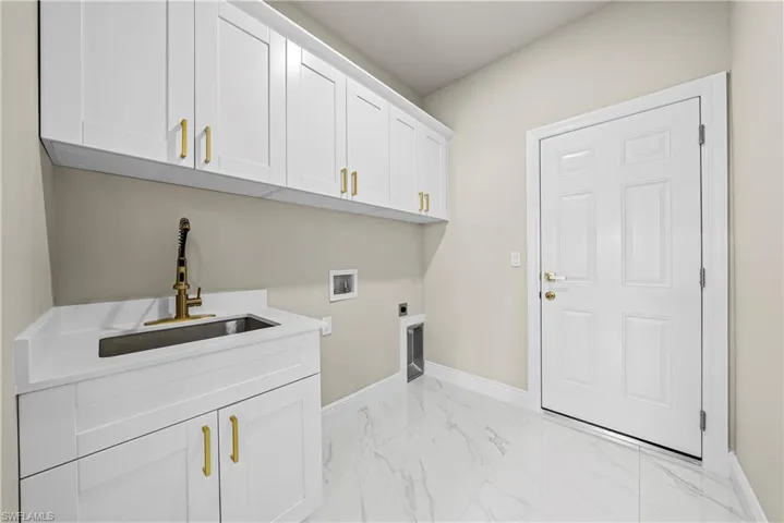 Laundry area featuring light marble finish flooring, hookup for a washing machine, cabinet space, and hookup for an electric dryer