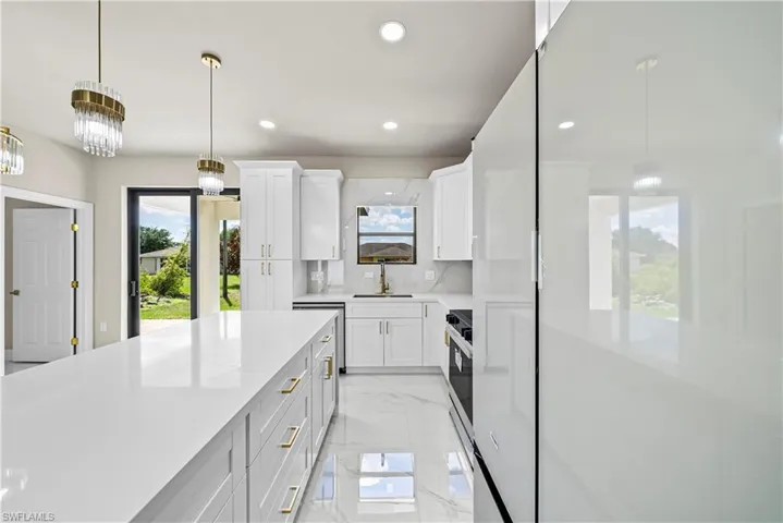 Kitchen with hanging light fixtures, white cabinetry, tasteful backsplash, and light stone countertops