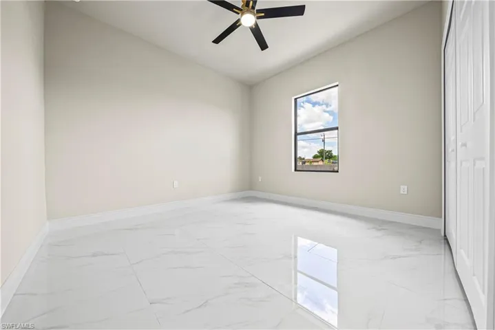 Empty room with light marble finish floors and ceiling fan