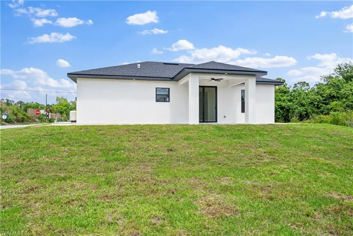 Back of house featuring a lawn, stucco siding, and a ceiling fan