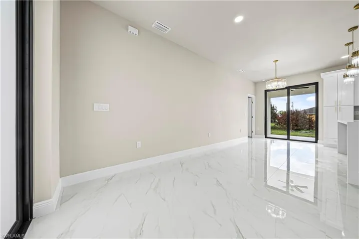 Unfurnished room with light marble finish flooring and hanging lights