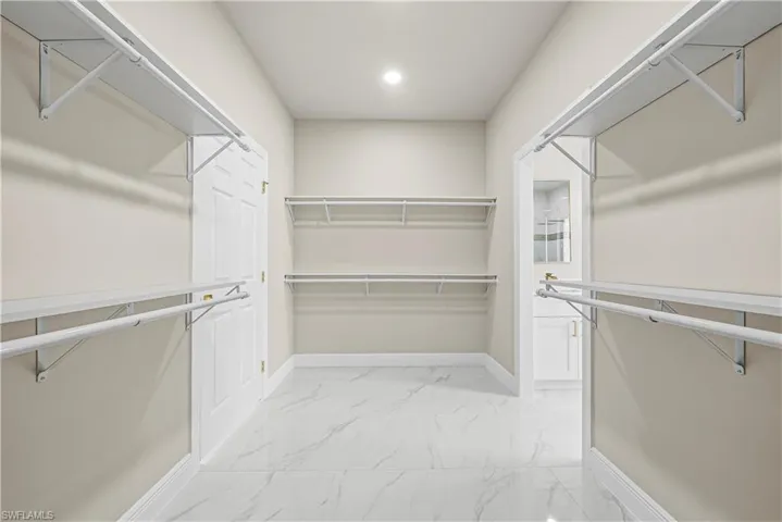 Walk in closet featuring light marble finish flooring