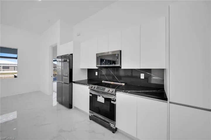 Kitchen featuring stainless steel appliances, white cabinetry, and modern cabinets