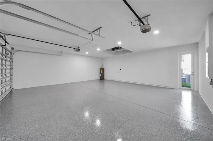 Garage with recessed lighting, a garage door opener, and water heater