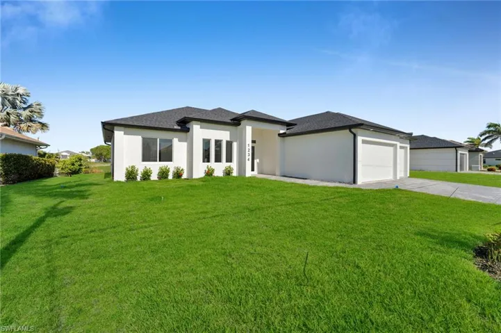 Prairie-style house with driveway, roof with shingles, a front yard, an attached garage, and stucco siding