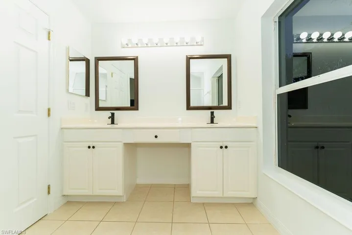 Full bathroom with light tile patterned floors and double vanity