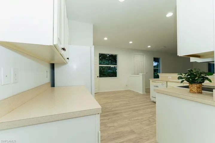 Kitchen featuring recessed lighting, white cabinets, light countertops, light wood-type flooring, and white appliances