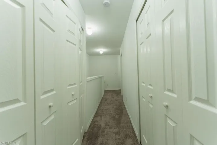 Hall with dark colored carpet and baseboards