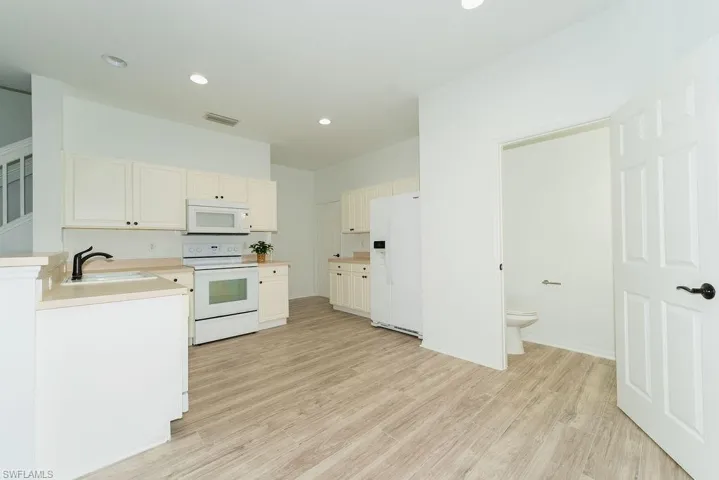 Kitchen with white appliances, recessed lighting, light countertops, light wood-style floors, and white cabinetry