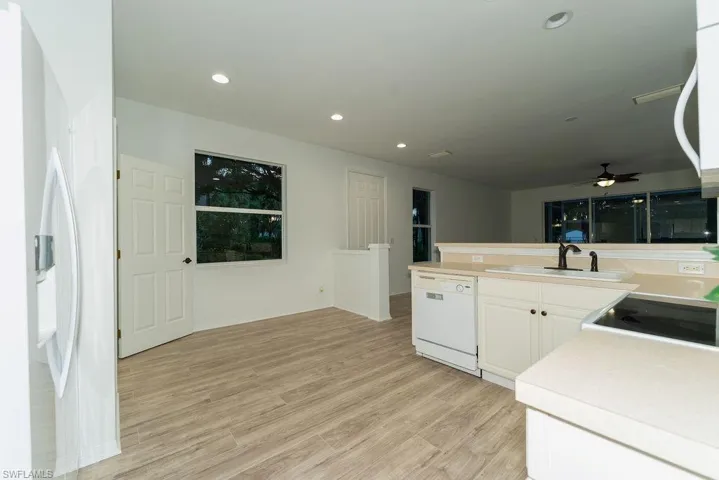 Kitchen featuring light countertops, light wood-style flooring, ceiling fan, recessed lighting, and white appliances