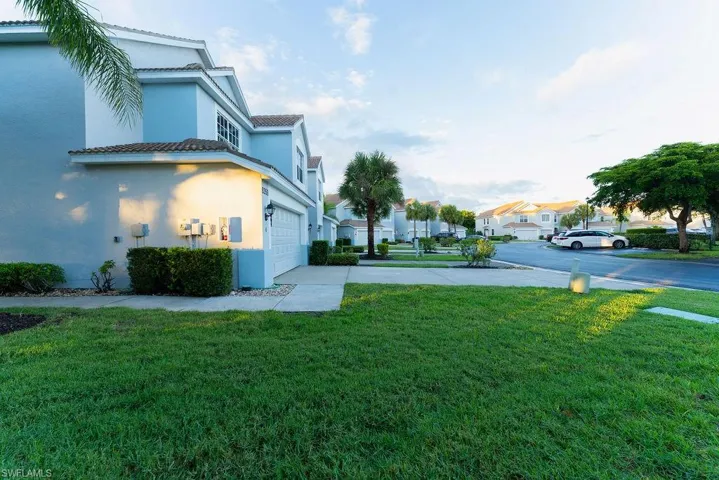 View of green lawn featuring driveway, a garage, and a residential view