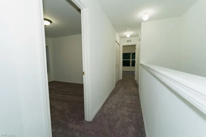 Hall featuring dark carpet and baseboards